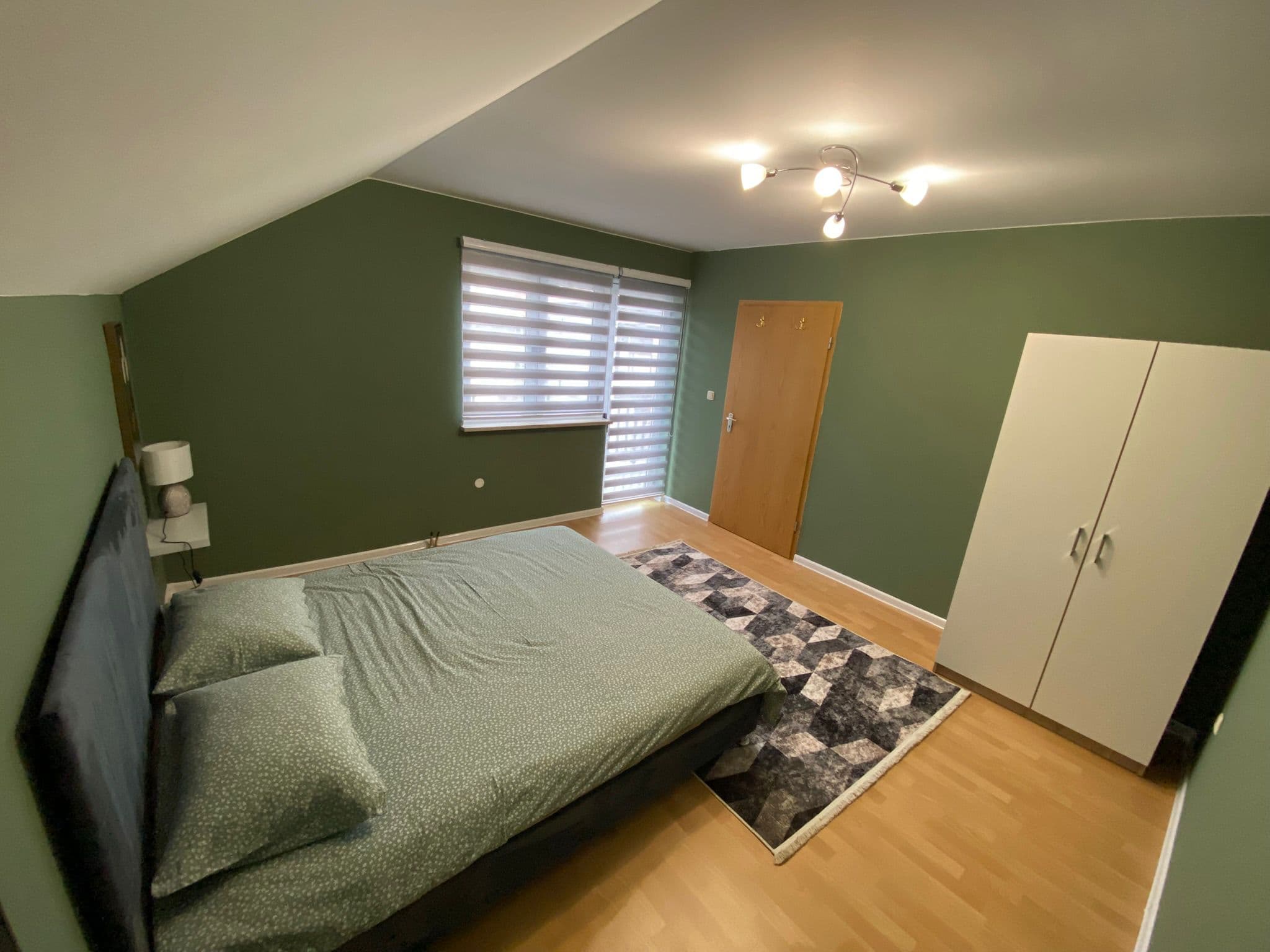 Comfortable double bedroom with green walls and natural light