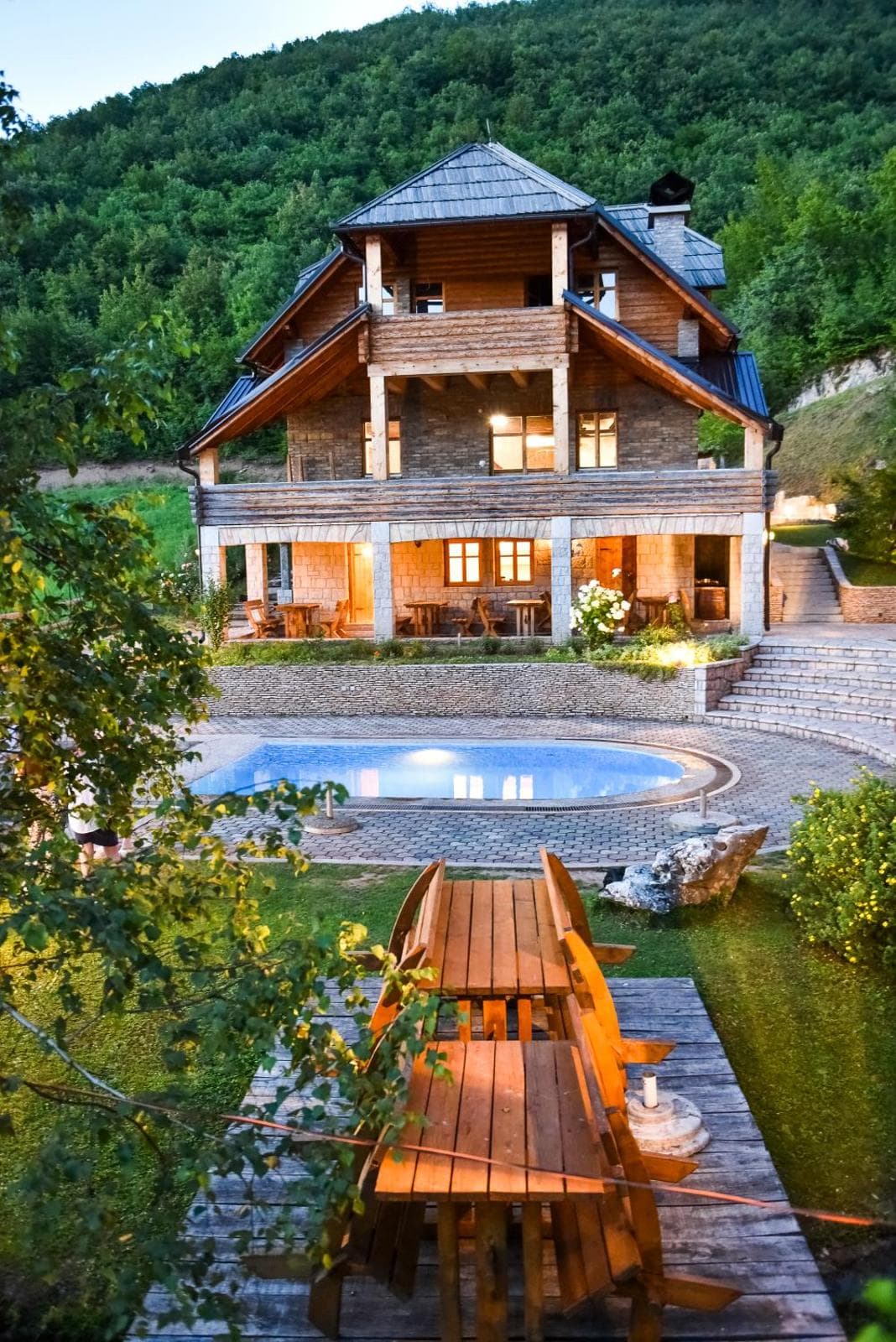 Full exterior of Villa 4 with wooden balconies, a swimming pool and forested hills