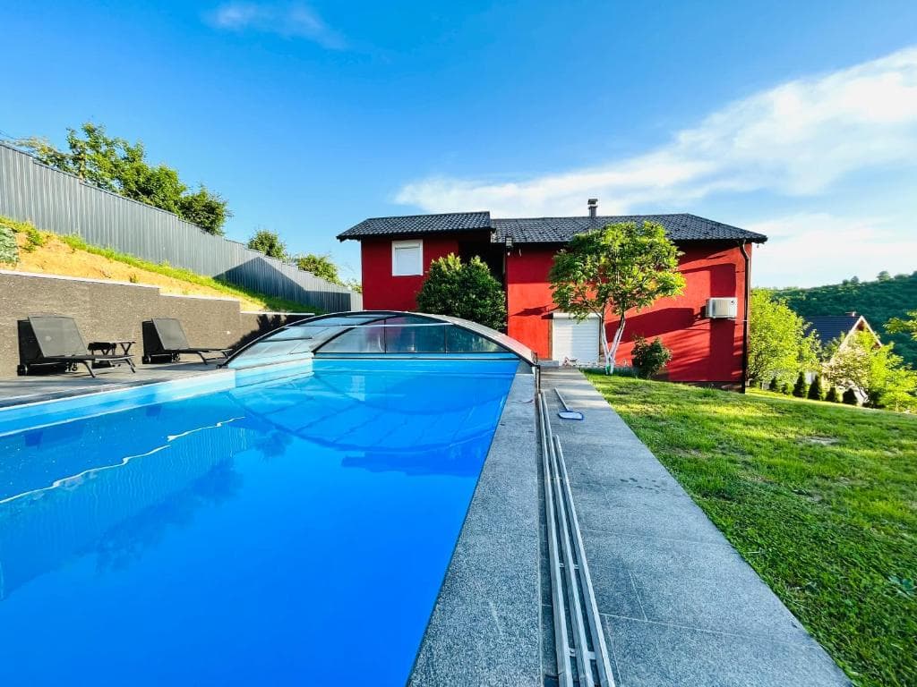 Red exterior of Villa 5 with a covered swimming pool and green garden